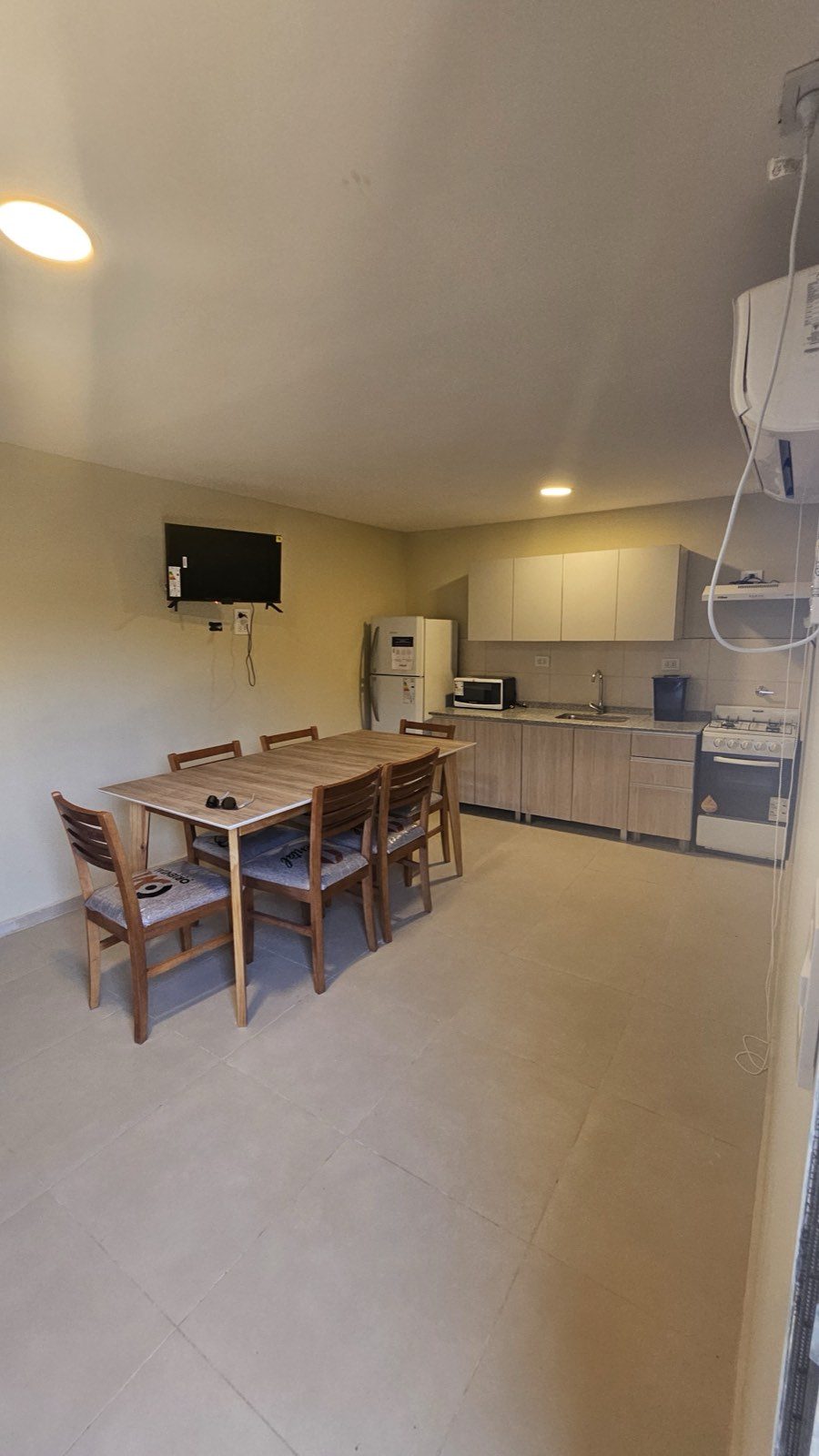 Cocina-comedor de la casa desde el otro extremo, con alacenas, microondas y dispenser de agua