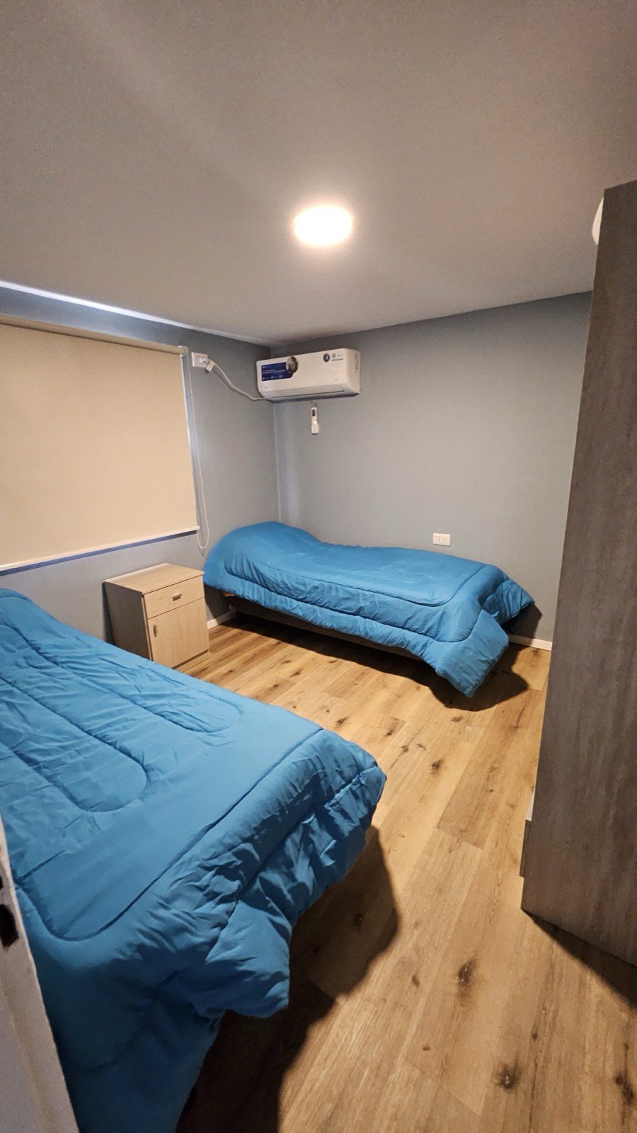 Habitación de la casa con dos camas individuales, mesa de luz y aire acondicionado