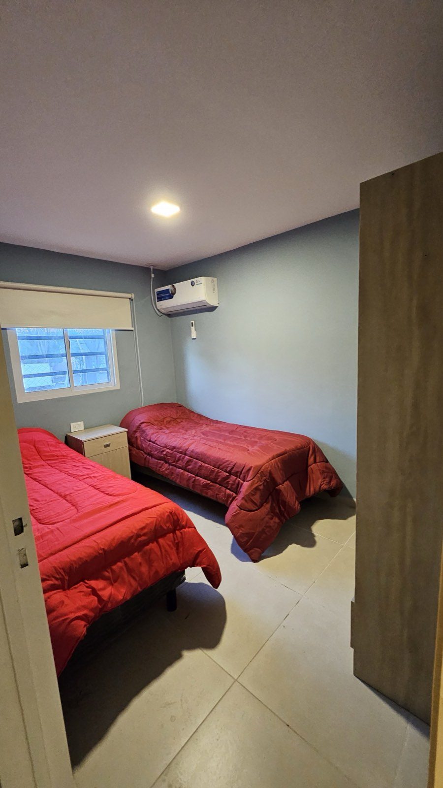 Habitación de la casa con dos camas individuales y ventana al exterior