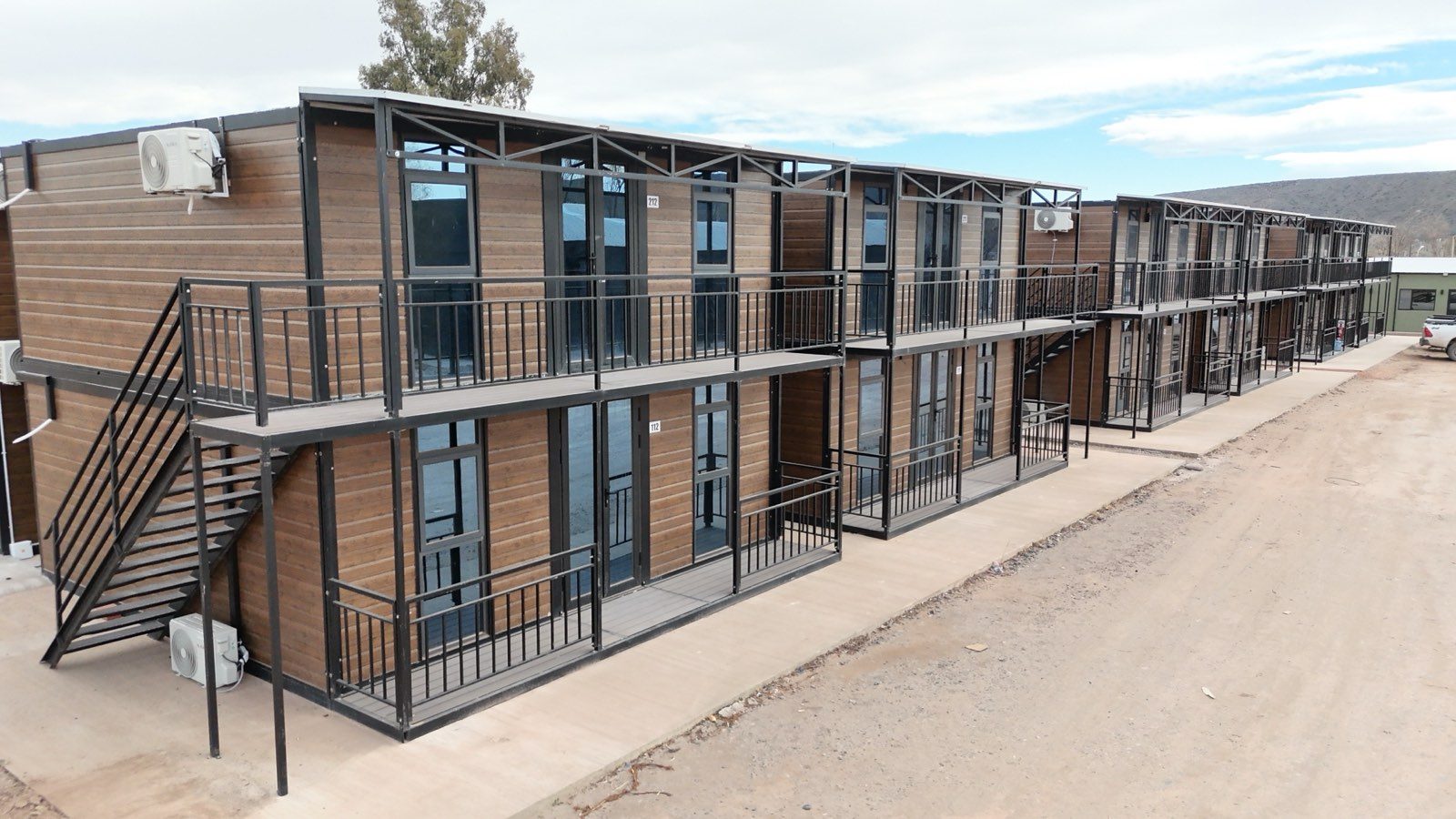 Módulos en perspectiva, con balcones corridos, barandas metálicas y escalera exterior