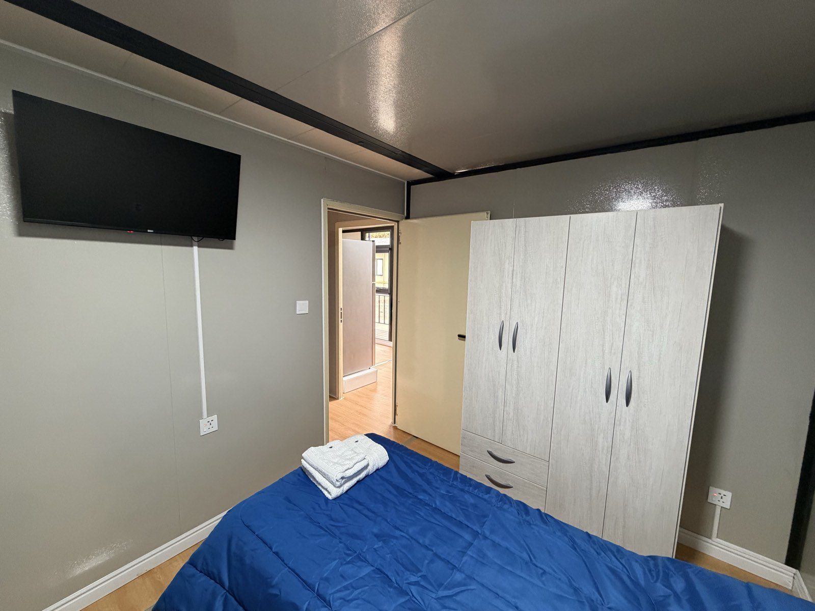 Habitación del departamento con televisor, placard y cama individual