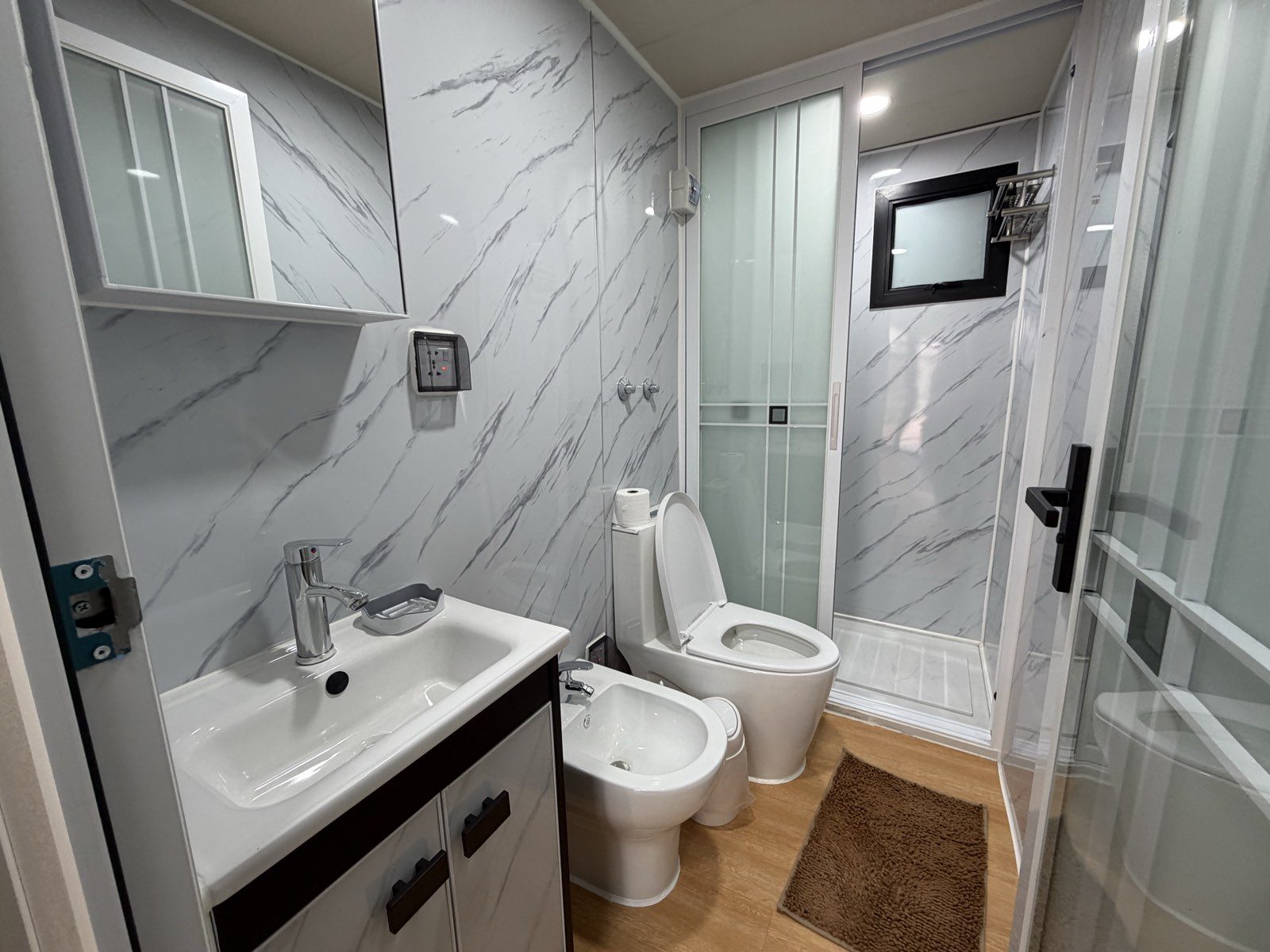 Baño del departamento, con bacha, inodoro, bidet y ducha con mampara